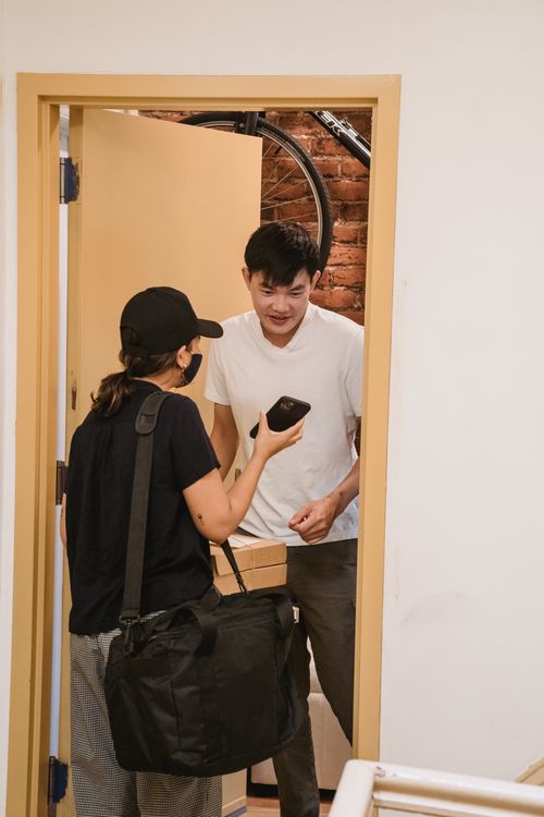 Free Delivery person handing over a package to a customer standing in his doorway. Stock Photo