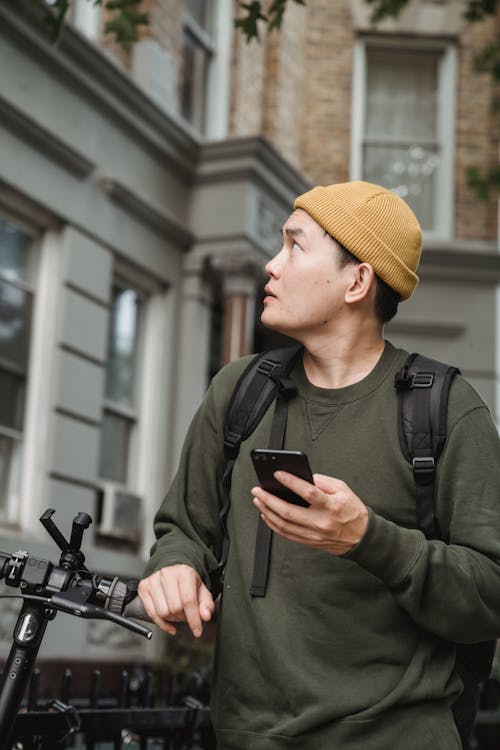 Man in Black Jacket and Yellow Knit Cap Holding Smartphone