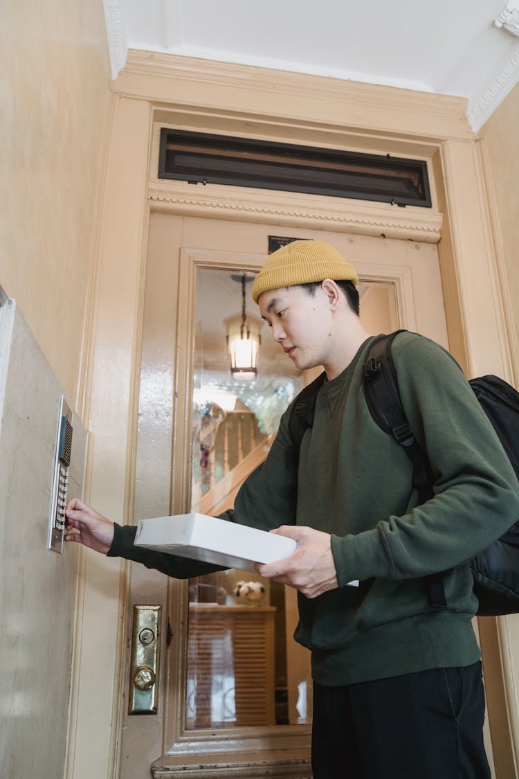 A Deliveryman Pressing An Intercom Doorbell