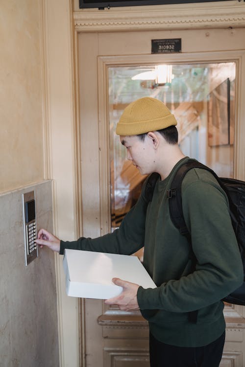Free A Deliveryman Pressing an Intercom Doorbell Stock Photo