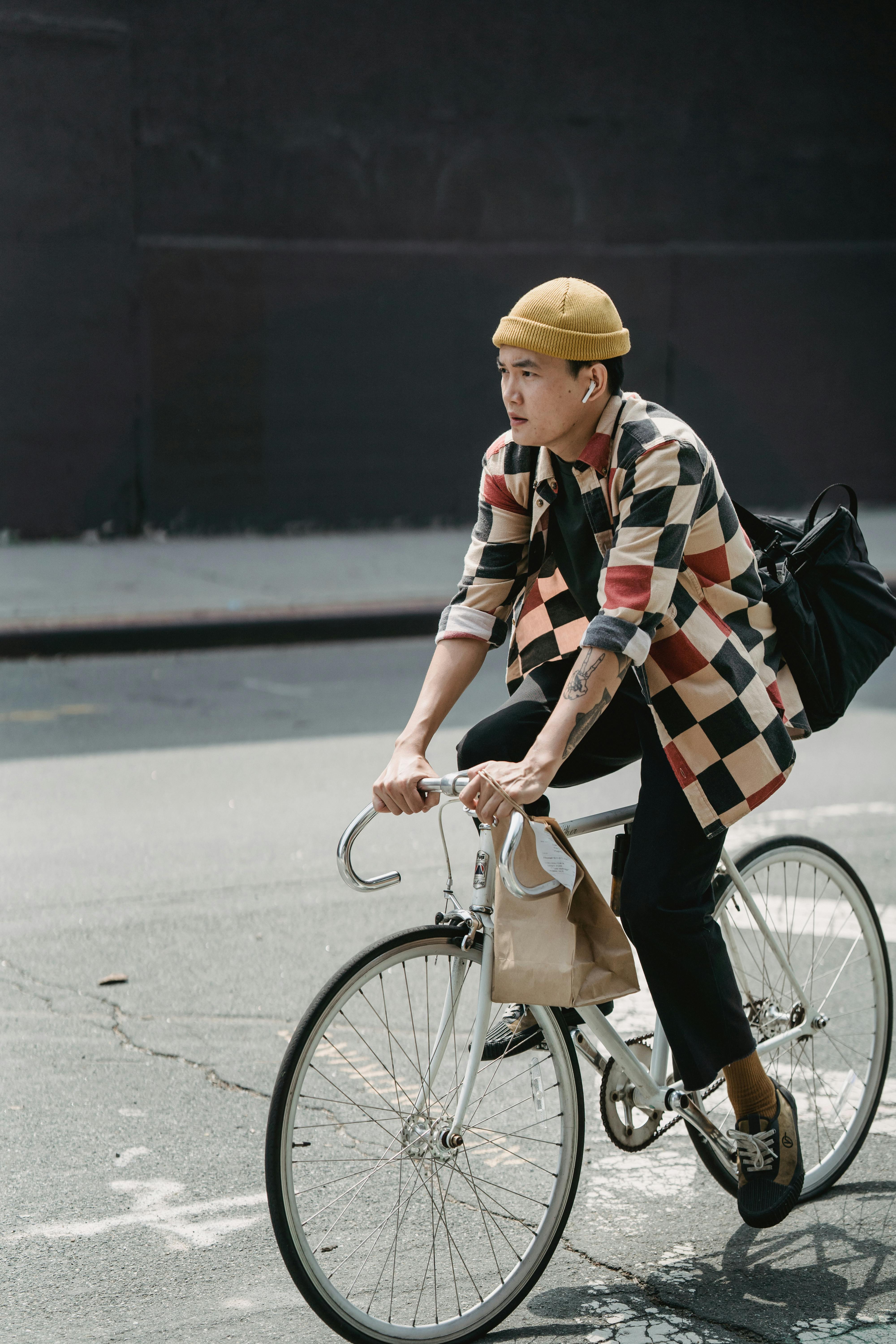 Asian courier riding a bicycle on city streets, showcasing urban delivery lifestyle.