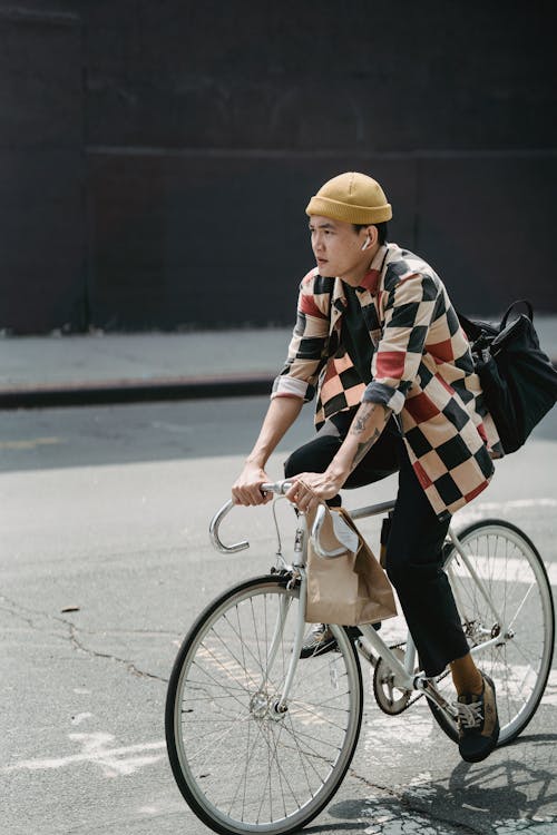 Free Woman in Black and White Plaid Long Sleeve Shirt and Brown Hat Riding on Bicycle during Stock Photo