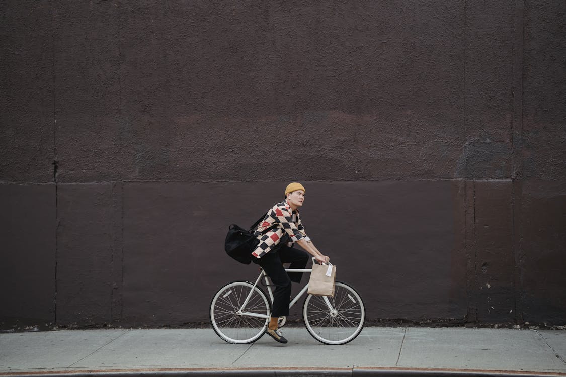 Man in Black Jacket and Black Pants Riding on Black Bicycle