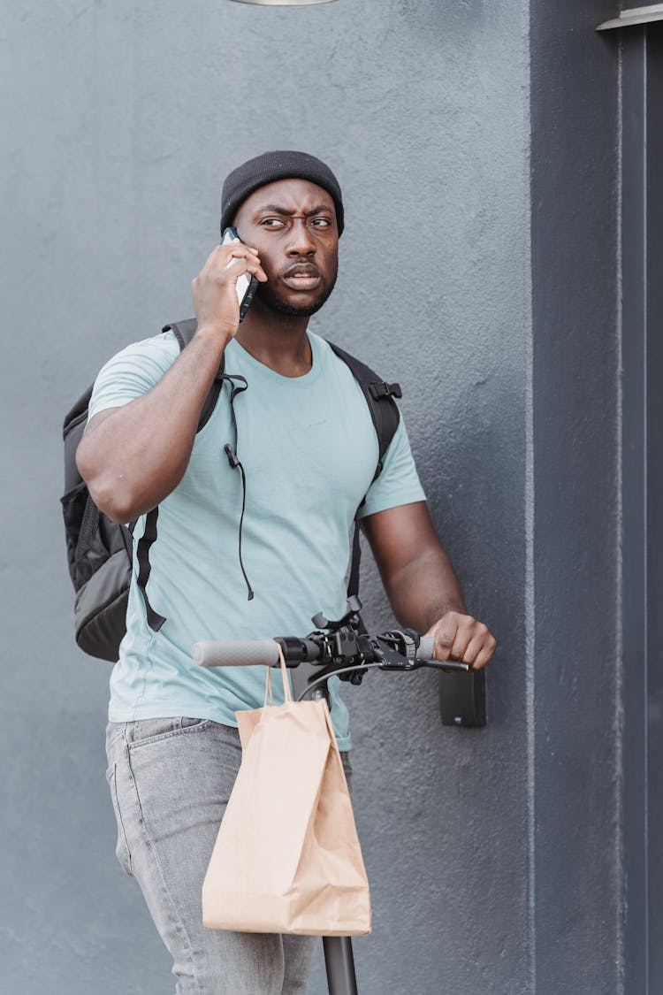 A Man In A Phone Call While On A Scooter