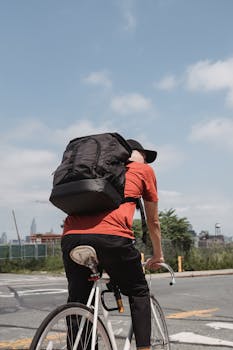 Cyclist with backpack riding on an urban street, showing active city lifestyle.