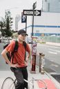 Man in Orange Tank Top and Black Pants With Black Cap Standing on Road