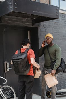 Two delivery workers exchanging packages outside a building entrance.