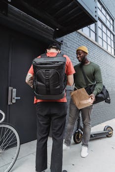 Two men interacting outside with an electric scooter and paper bag.
