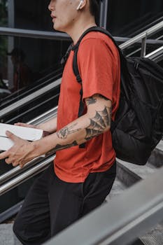 Side view of a delivery man with a tattoo carrying packages outdoors.