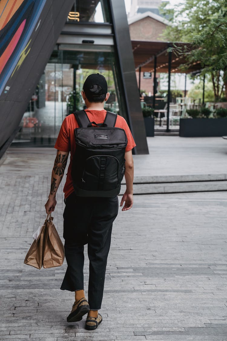 A Delivery Man With A Back Pack And Paper Bags