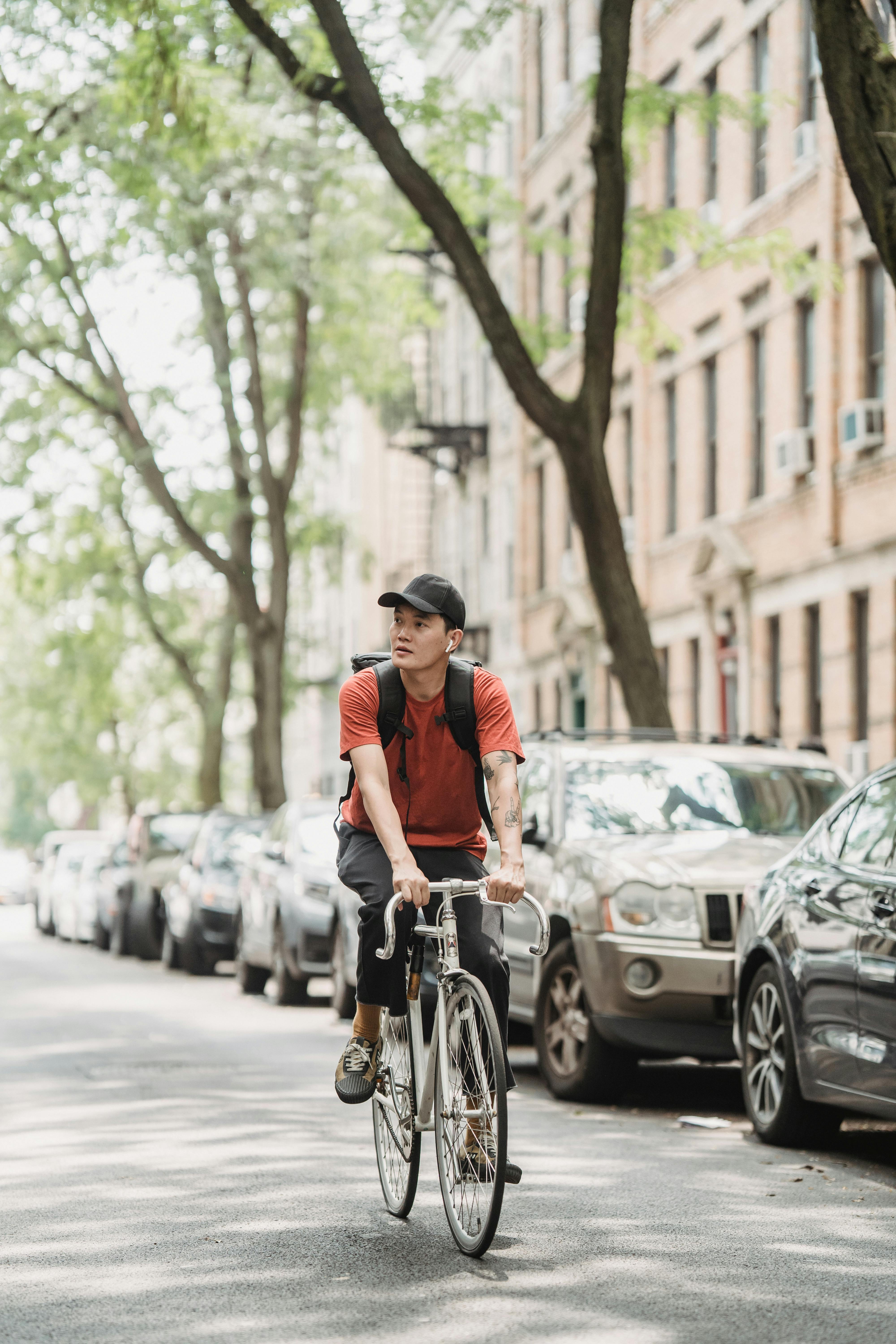 photo of a man riding a bicycle near vehicles