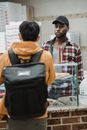 Man in Plaid Shirt Standing in Front of Man in Orange Hoodie Carrying Backpack