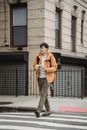 Man in Yellow Jacket and Gray Pants Holding Green Plastic Bag