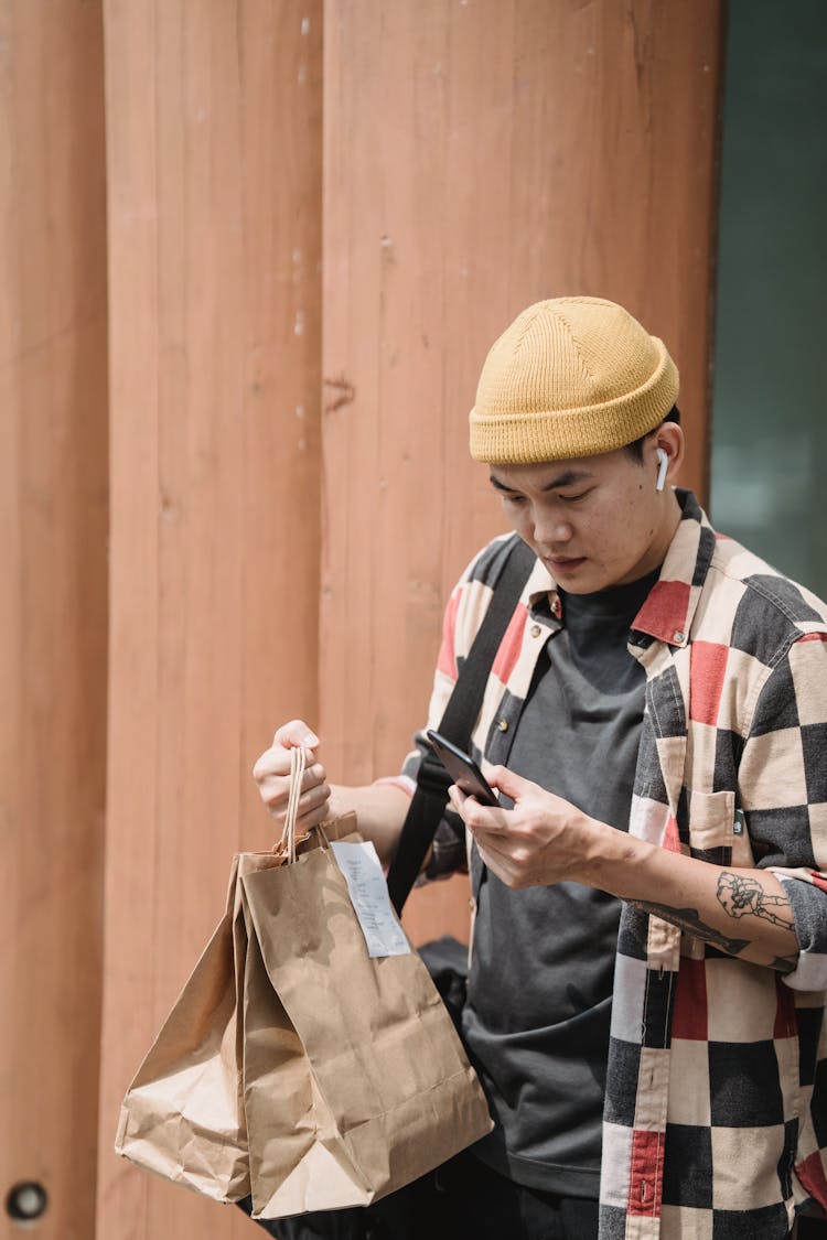 Courier With Bags Checking Order On Cellphone