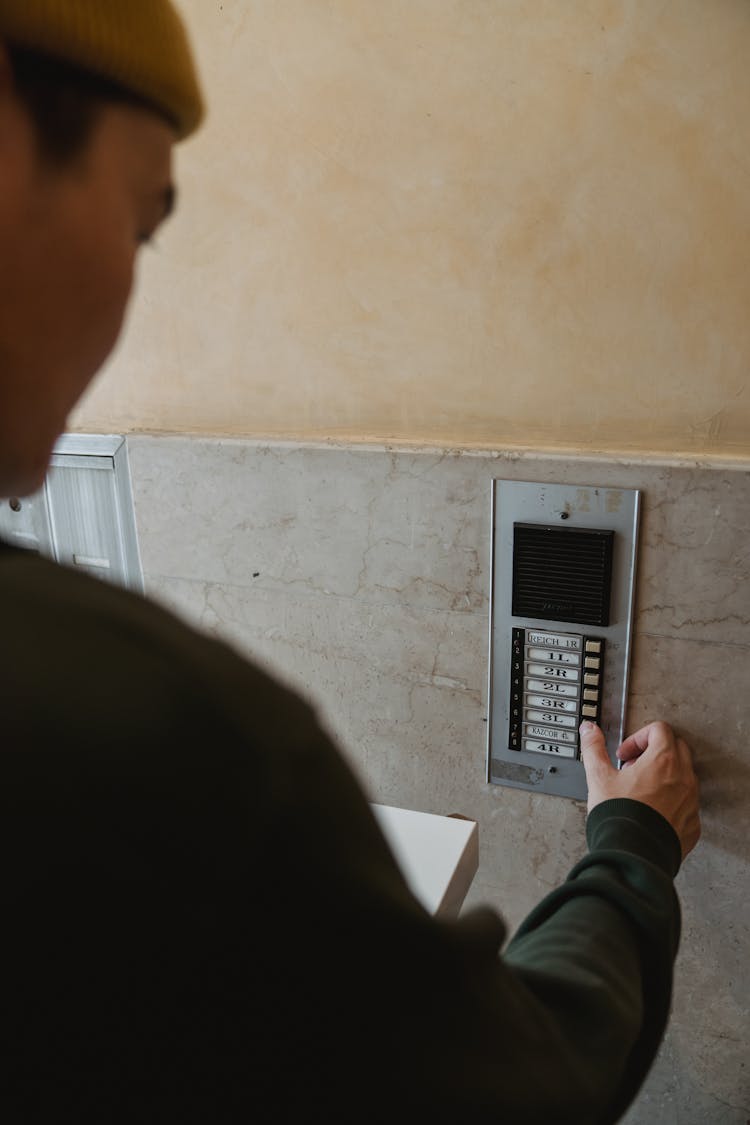 Man In Black Long Sleeve Shirt Pressing A Button On Intercom