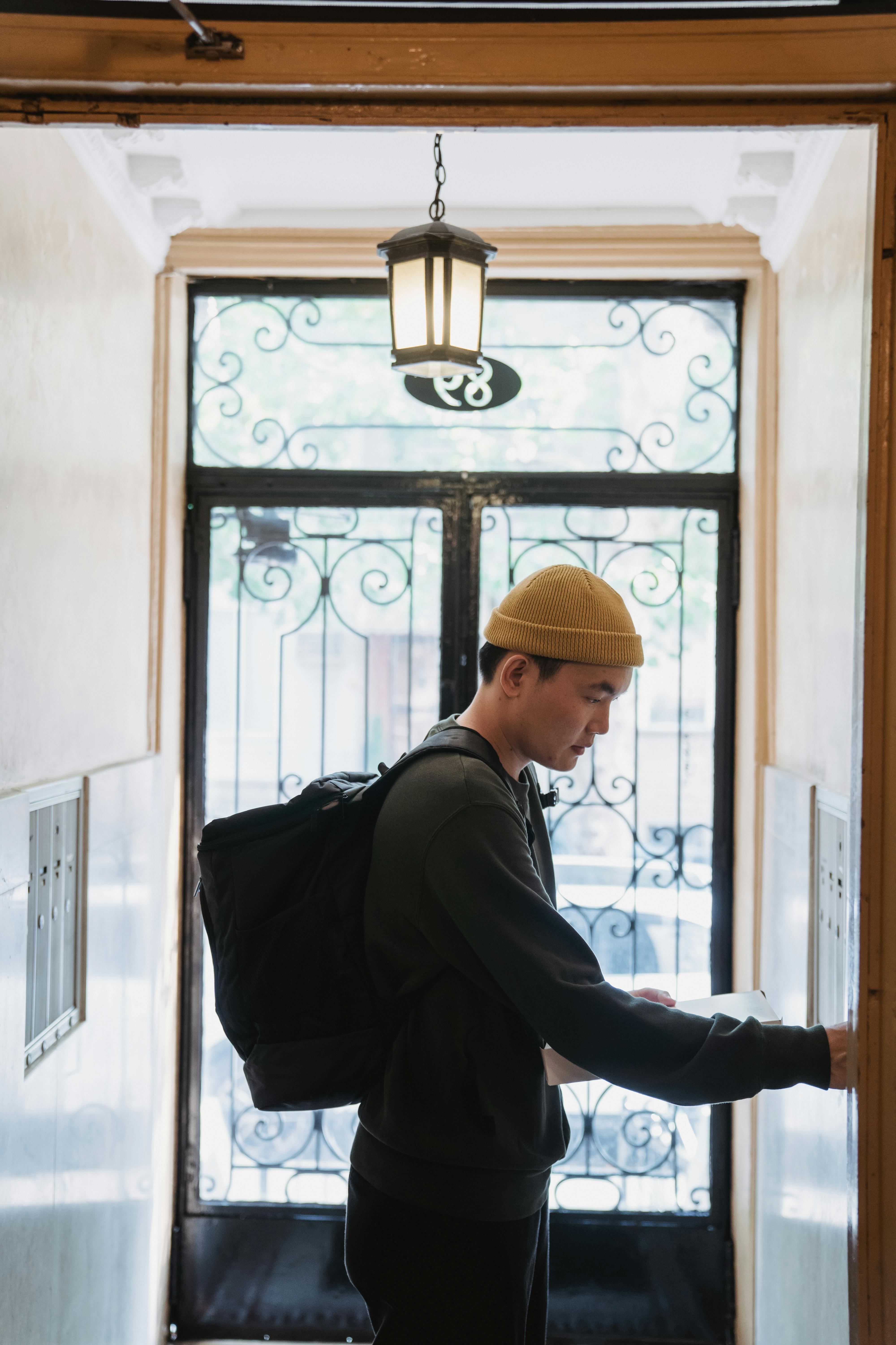 man in black jacket and brown cap standing in front of the elevator