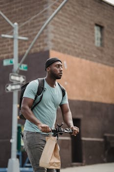 Man riding electric scooter with paper bag on city street, showcasing urban delivery.