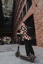Man in Black and Red Checkered Long Sleeve Shirt and Black Pants Standing Beside Brown Brick