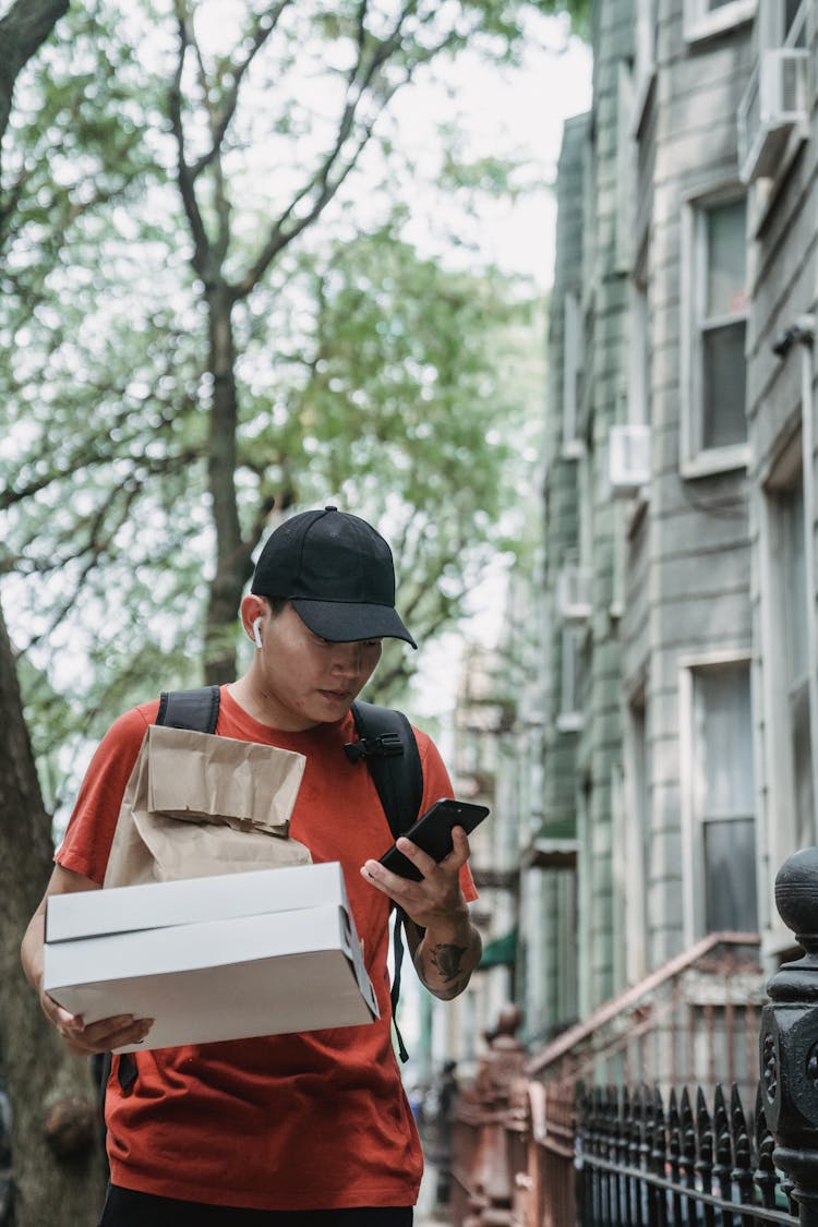 Courier With Boxes Checking Mobile Delivering Order