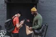 Man in Green Jacket and Orange Apron Holding Smartphone