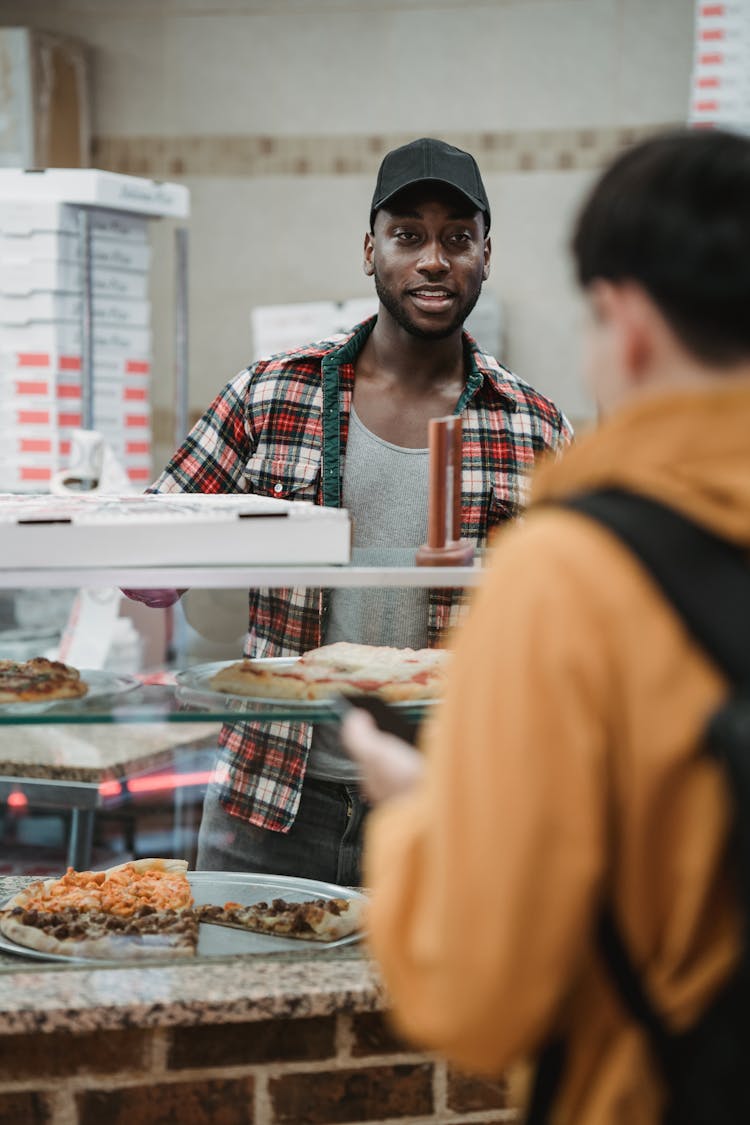 Man Selling Pizza To A Boy 