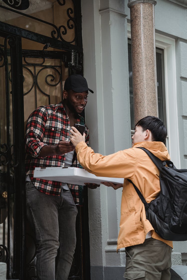 A Man Receiving A Parcel At The Front Door