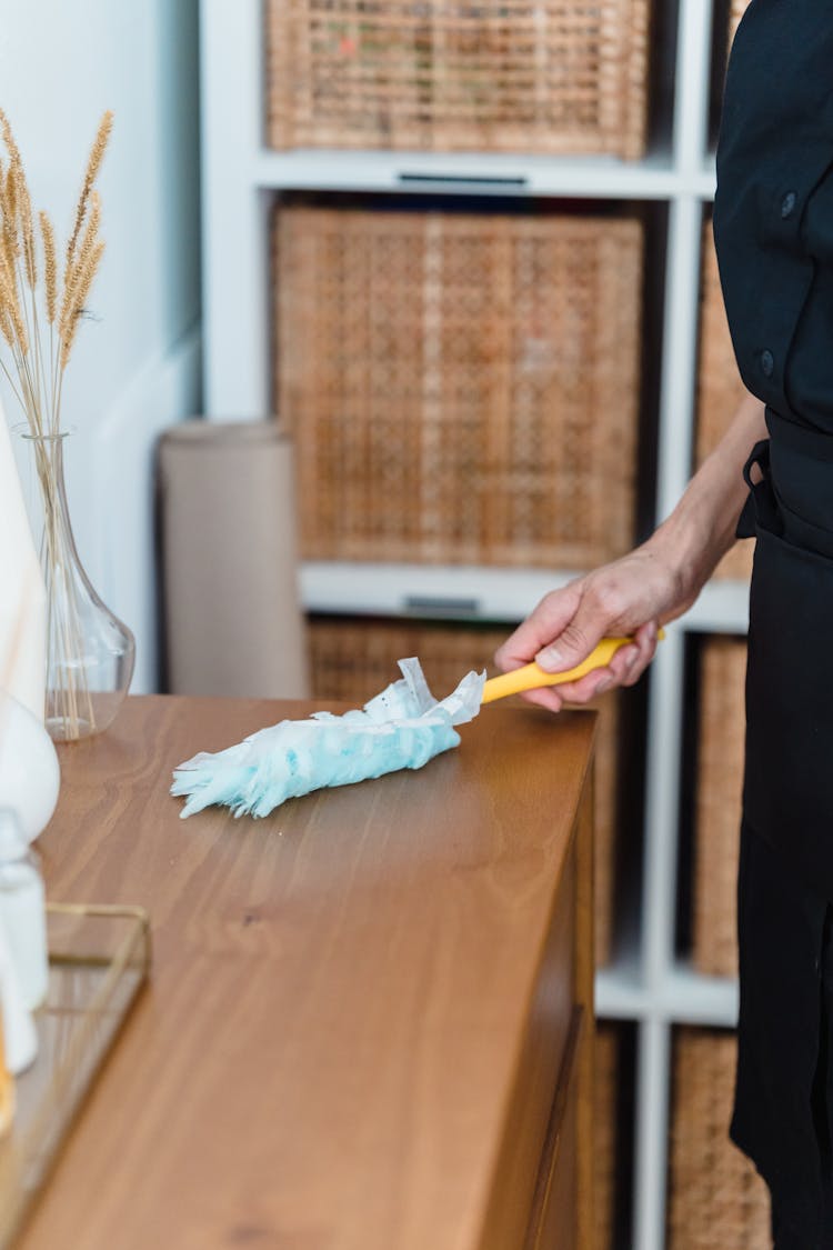 Woman Cleaning The Top Of A Dresser 