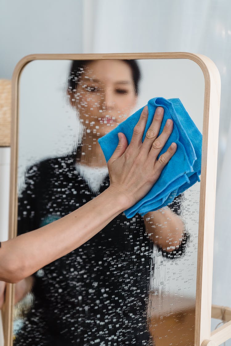 A Person Wiping A Wet Mirror