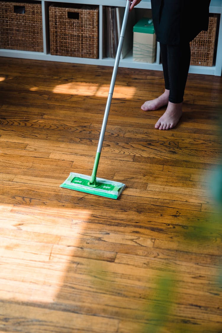 A Person Holding Green Floor Sweeper