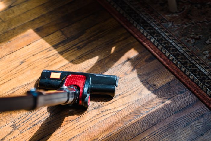 Red upright vacuum cleaner on a wooden floor near a rug