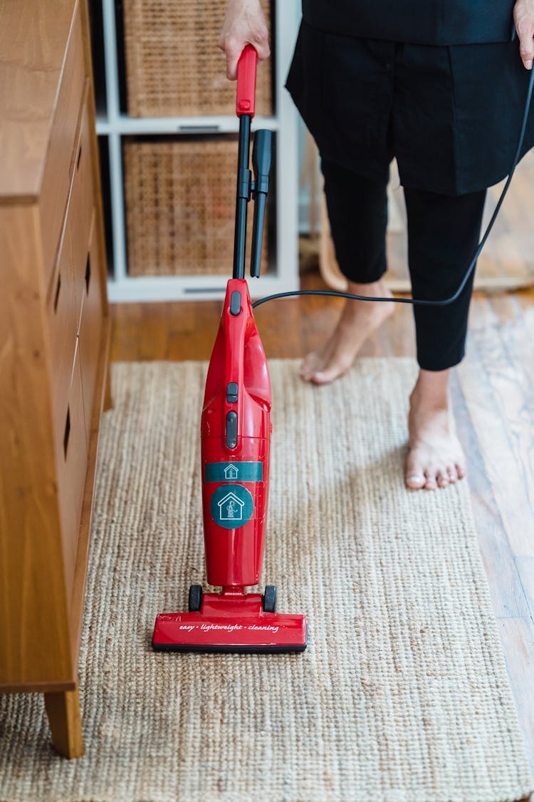 A Person Cleaning A Carpet Using A Vacuum Cleaner