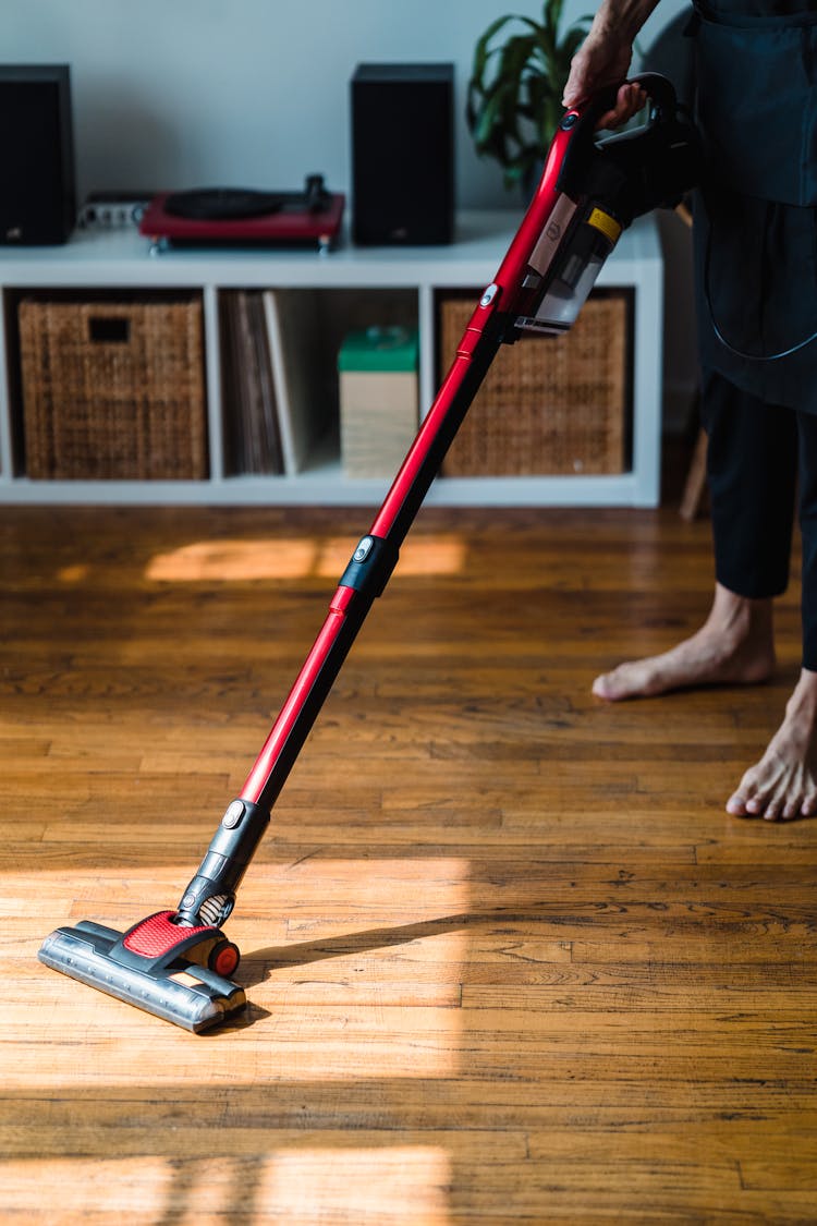 A Person Cleaning A Wooden Floor Using A Vacuum Cleaner