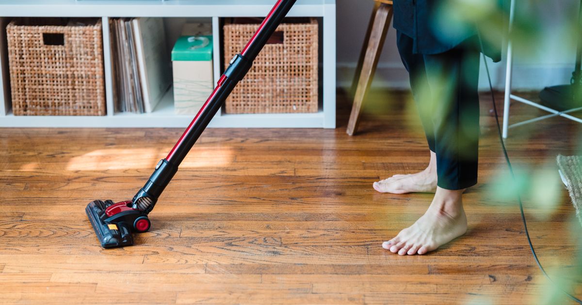 Running a cordless stick vacuum over a wooden floor