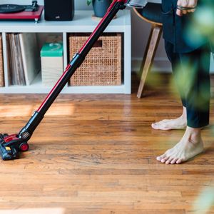 Running a cordless stick vacuum over a wooden floor