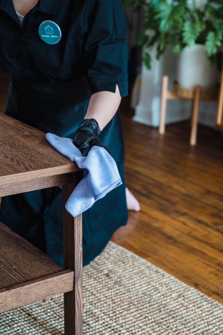 A Person Cleaning The Wooden Table