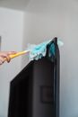 A Person Dusting a Flat screen TV
