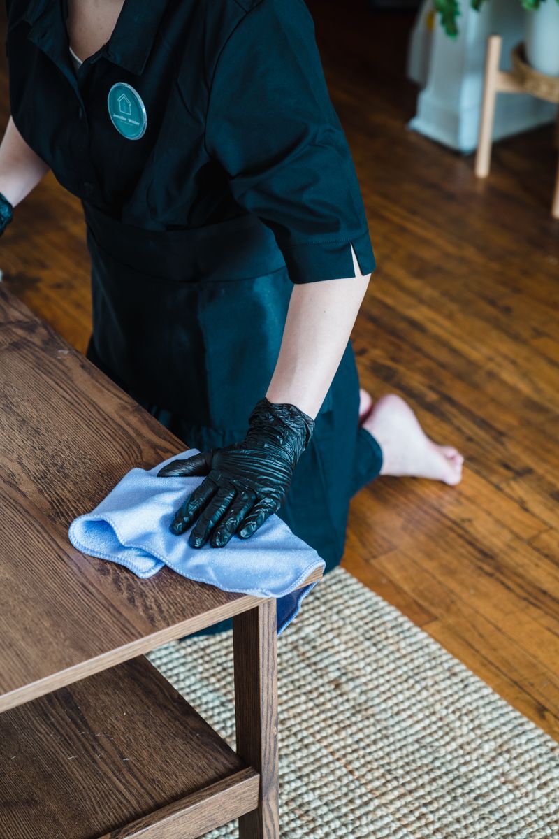 A professional cleaner wiping a wooden table