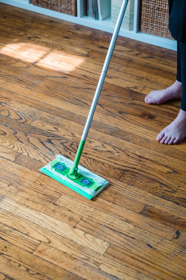 A Person Sweeping A Wooden Floor