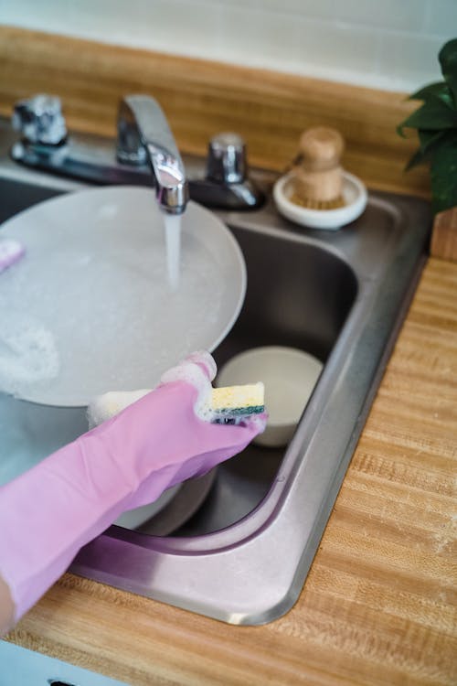 A Person Rinsing a Plate on Faucet