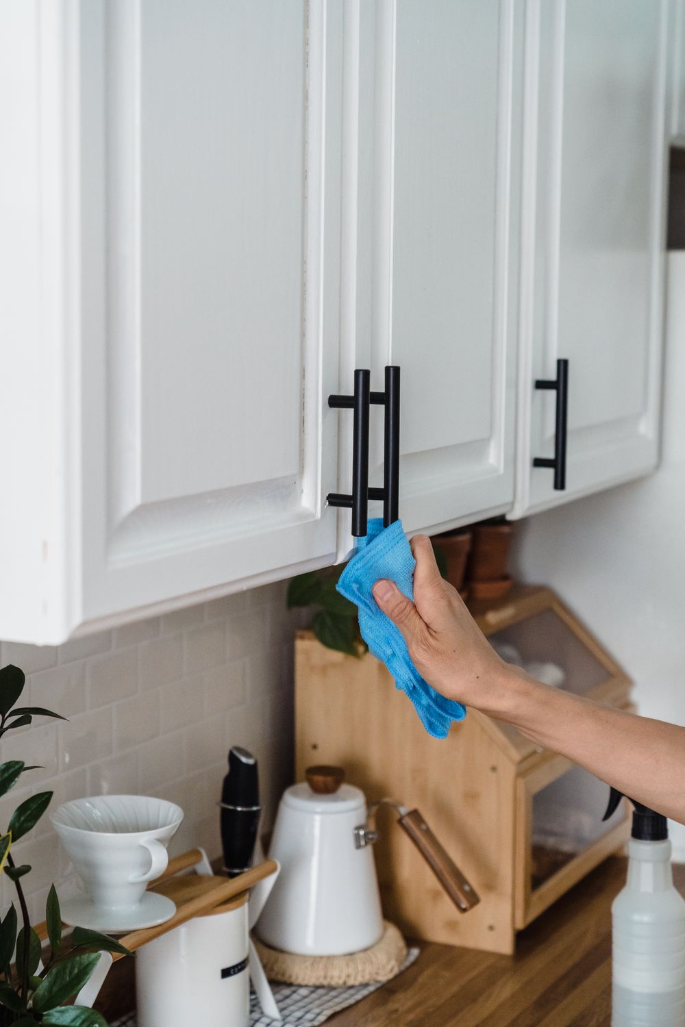 Carefully wiping the handles of a kitchen cabinet