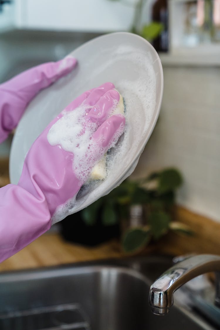 A Person Washing A Plate 