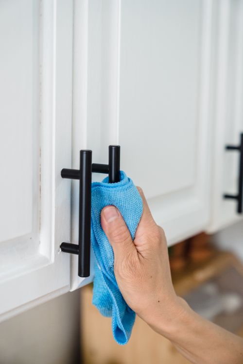 A Person Cleaning the Handles of Cabinet using a Rag · Free Stock Photo
