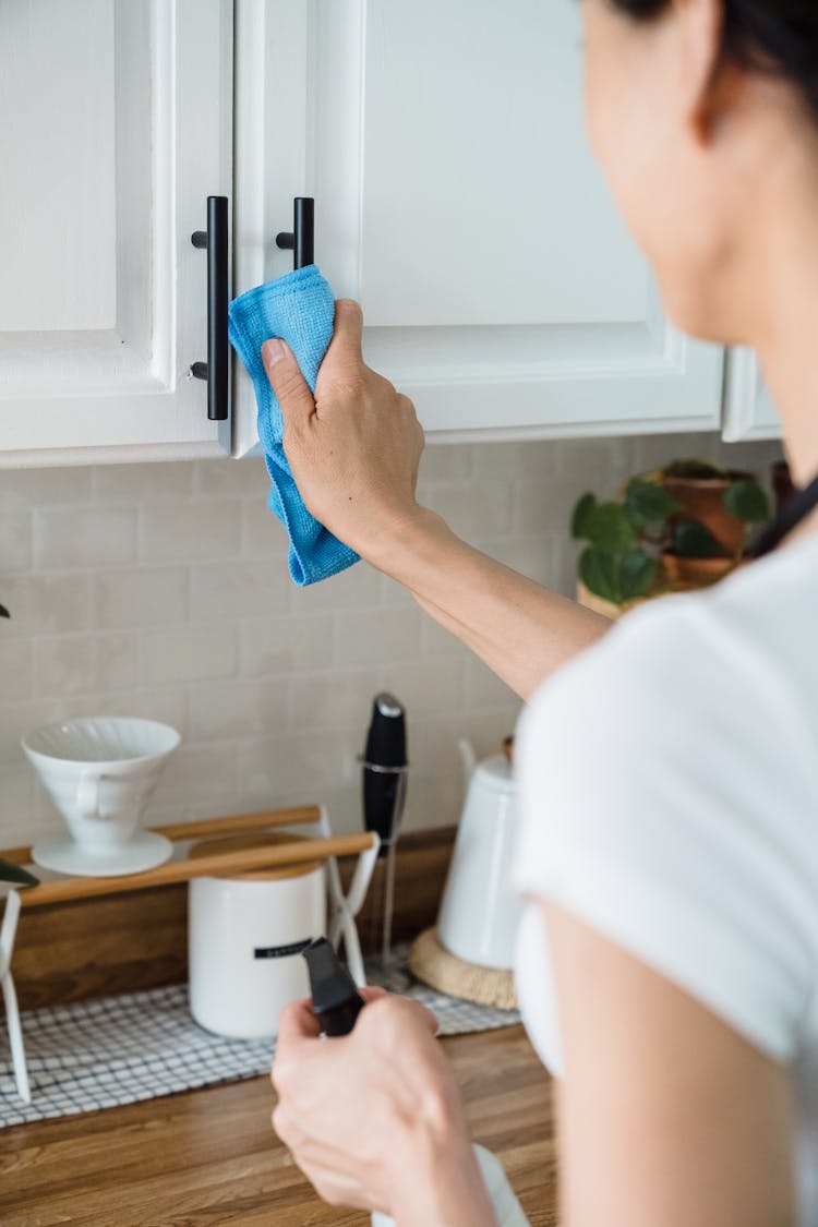 Person Cleaning The Handle Of A Cabinet