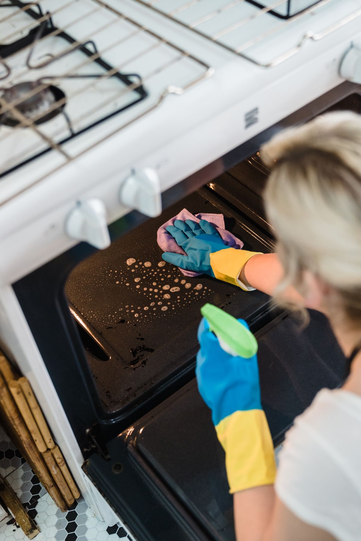A cleaner in protective gloves deep cleaning an oven interior during a full deep clean.