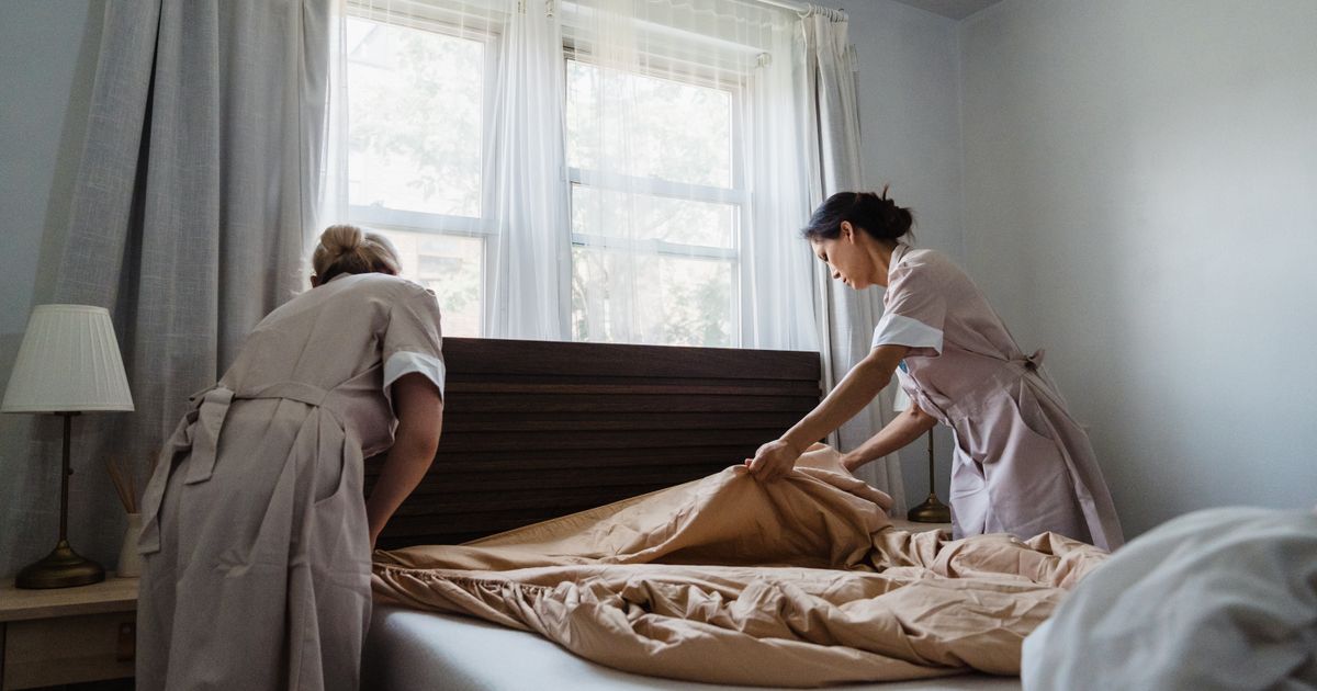 Zwei Housekeeping-Kräfte beziehen ein Bett in einem hellen Zimmer, Symbolbild für Hotelreinigung