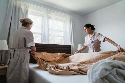 Free Women Putting Bed Sheet in a Bed Stock Photo