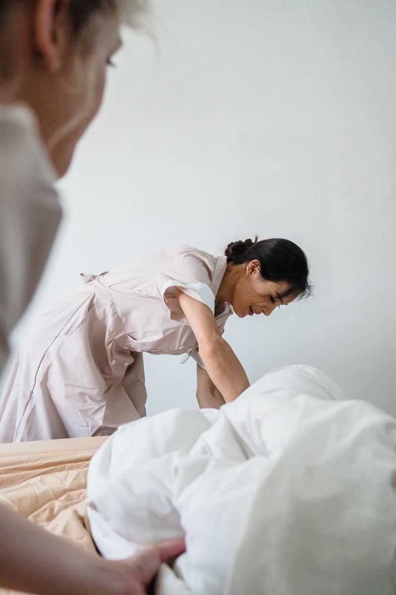 Housekeeper making a bed with white linen between guest stays