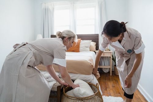 Cleaner tidying a bedroom