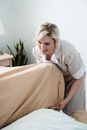 A Happy Housekeeper Tidying a Bed