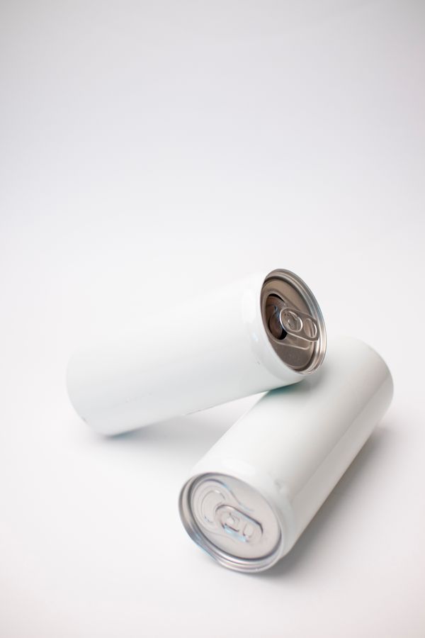 Uploaded product photo of two unlabelled slim drink cans on a light surface — photo by Lesya Terekhova on Pexels